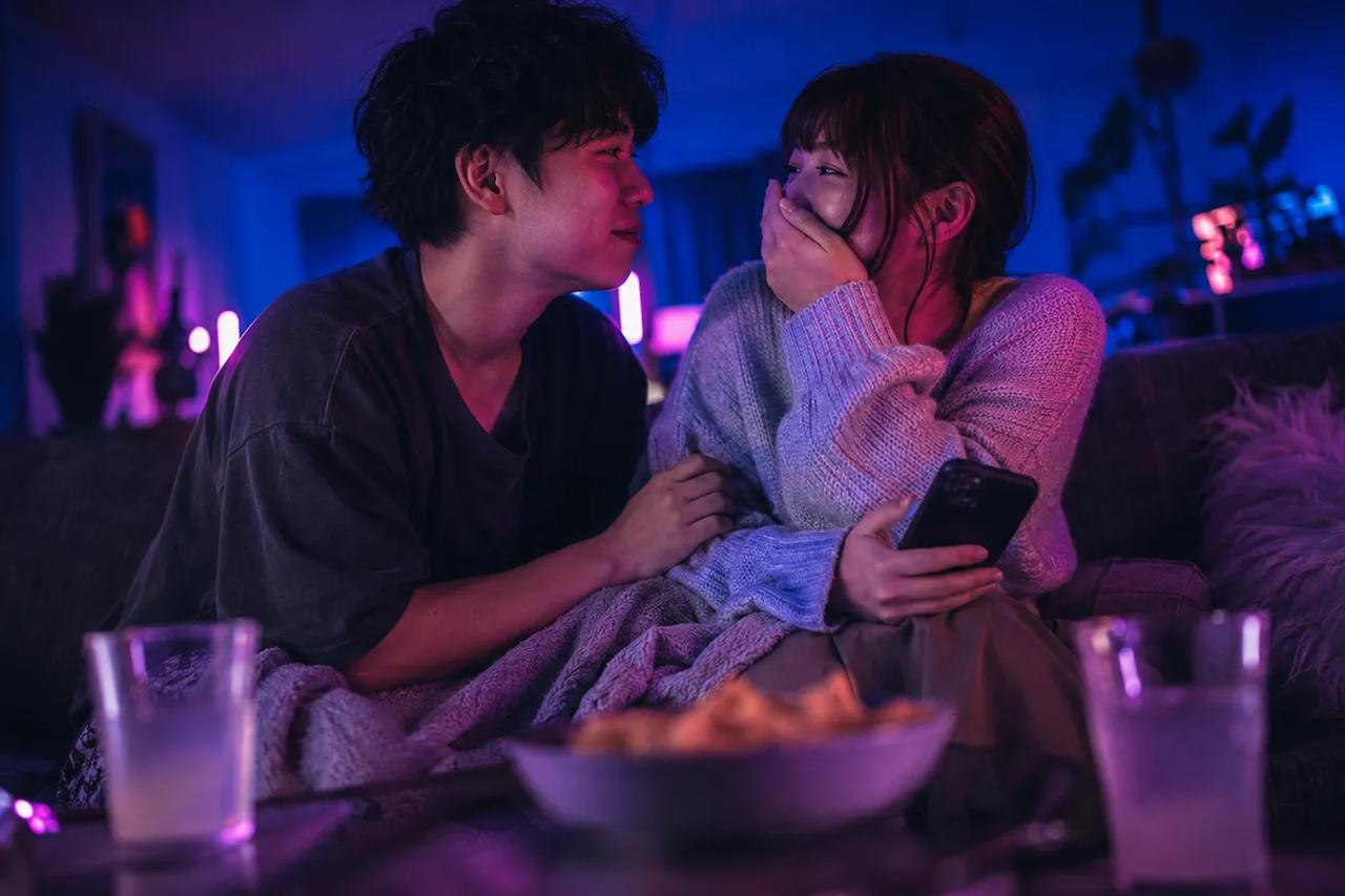 A couple sitting together on a couch, laughing and enjoying a fun quiz game during date night