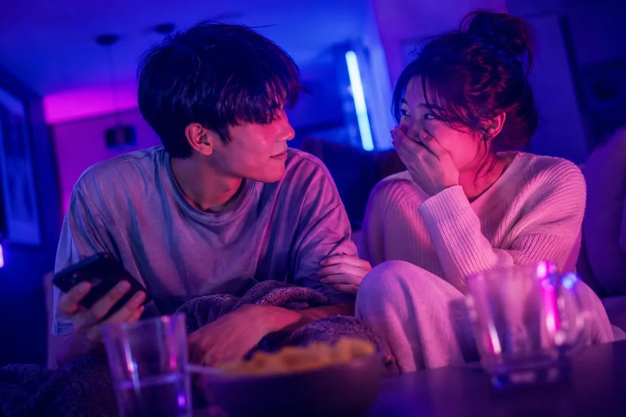 소파에 함께 앉아 데이트 밤에 즐거운 퀴즈 게임을 하며 웃고 있는 커플의 모습