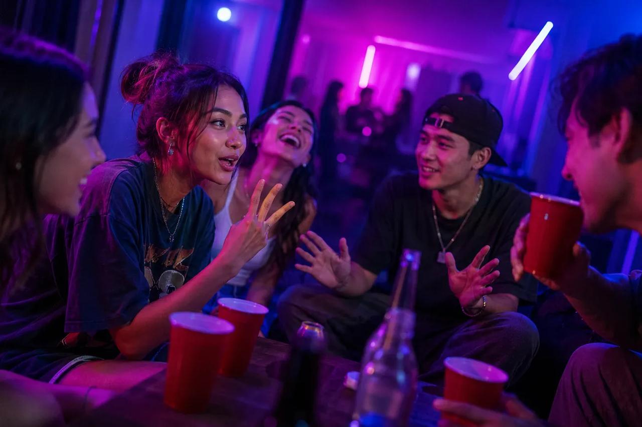 Parta přátel sedící v kruhu a hrající hru 21 otázek na party