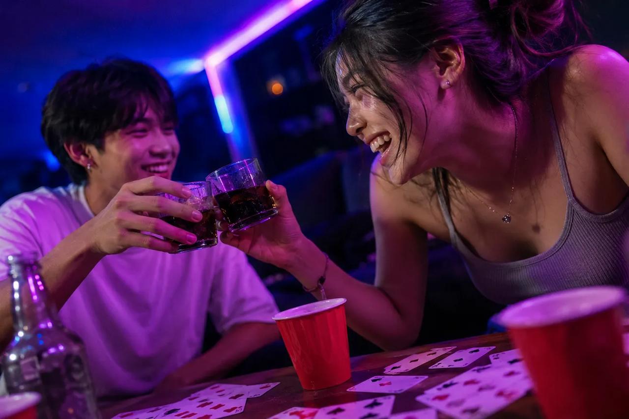 ภาพคนสองคนกำลังเล่นเกมวงเหล้าด้วยกันในคืนเดตไนต์สุดโรแมนติก