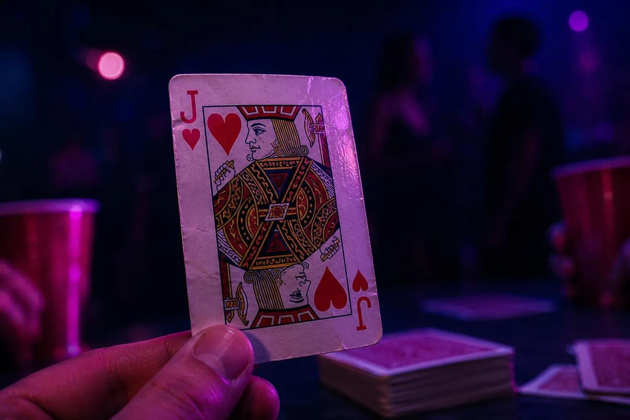 Dos jugadores volteando cartas para adivinar si la siguiente es mayor o menor en un juego para tomar