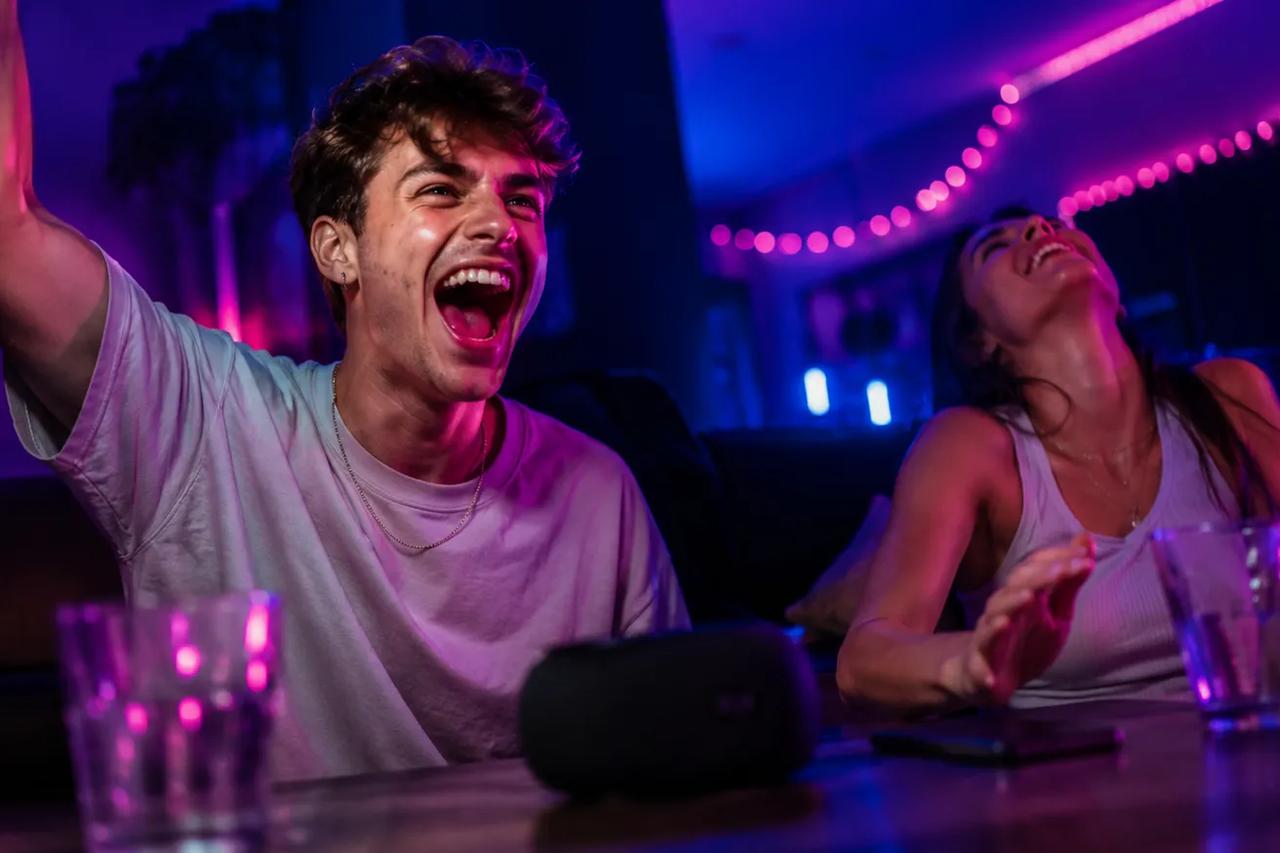 Dos personas jugando un blind test musical para tomar con un celular y una bocina