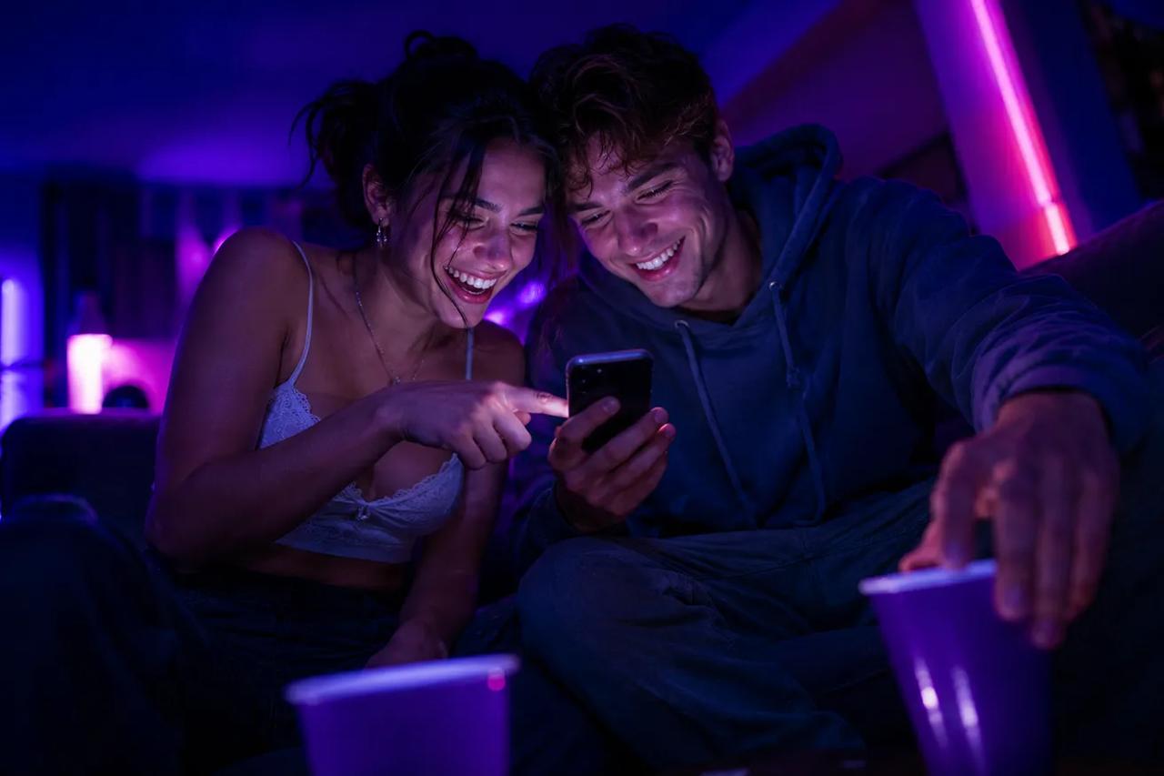 Una pareja jugando la app TOZ en el celular durante un juego para tomar de a dos